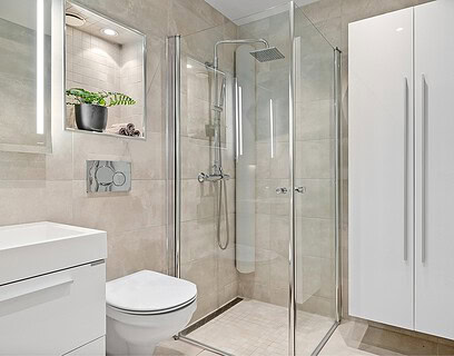 Baño de hotel con mampara de ducha de vidrio transparente y perfilería cromada en espacio minimalista
