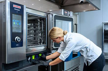 Cocinera insertando cartucho de limpieza en horno combinado RATIONAL iHexagon en cocina profesional
