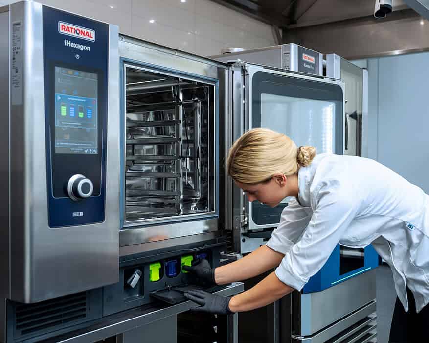 Cocinera insertando cartucho de limpieza en horno combinado RATIONAL iHexagon en cocina profesional