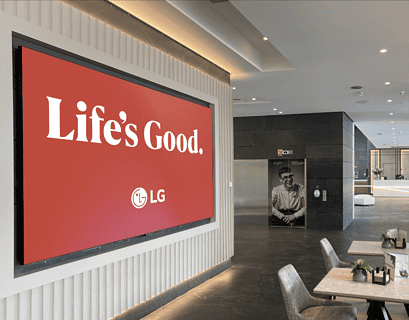 Pantalla LED de LG con campaña Life's Good instalada en el lobby de un hotel moderno con zona de recepción al fond
