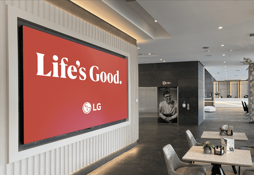 Pantalla LED de LG con campaña Life's Good instalada en el lobby de un hotel moderno con zona de recepción al fond