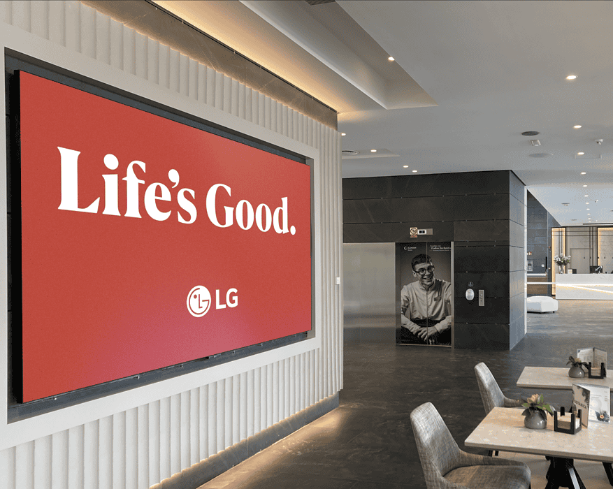 Pantalla LED de LG con campaña Life's Good instalada en el lobby de un hotel moderno con zona de recepción al fond