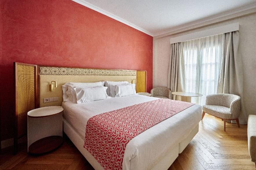 Habitación renovada del NH Collection Palacio de Córdoba con pared roja caldero y cabecero inspirado en la técnica del Cordobán