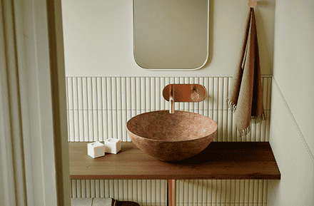 Lavabo Bathco New Lys con acabado Tierra de tonos cálidos y orgánicos sobre encimera de madera en baño de estilo natural