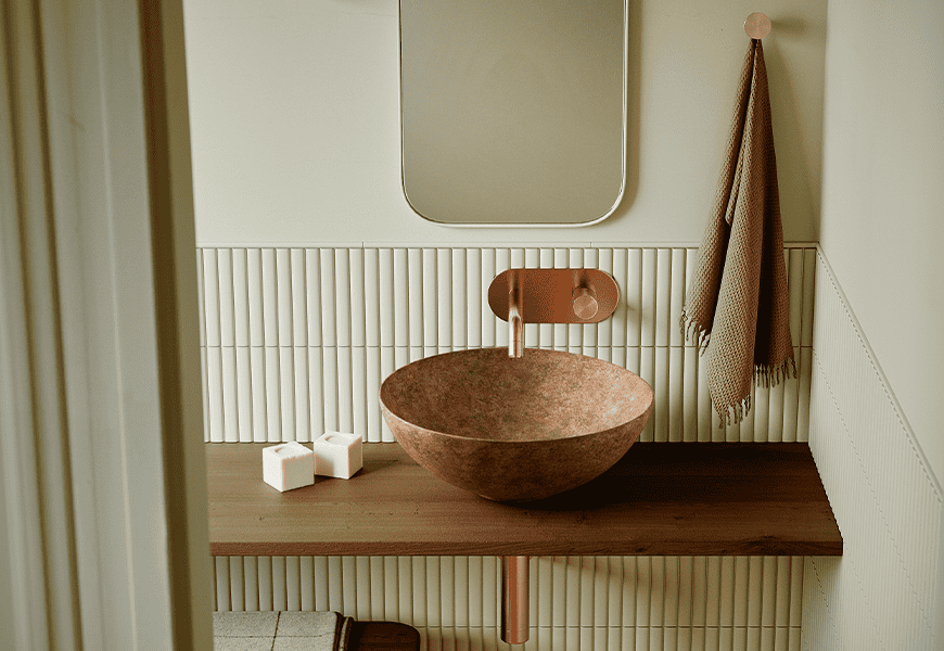 Lavabo Bathco New Lys con acabado Tierra de tonos cálidos y orgánicos sobre encimera de madera en baño de estilo natural