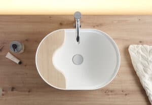 Lavabo oval Seceda de Bathco en Solid Surface blanco sobre encimera de madera con bandeja integrada de bambú