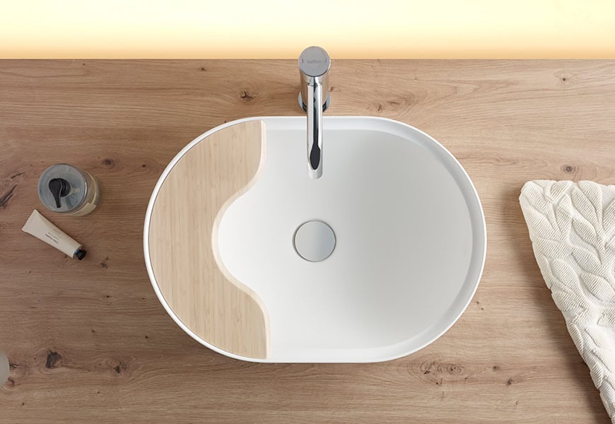 Lavabo oval Seceda de Bathco en Solid Surface blanco sobre encimera de madera con bandeja integrada de bambú