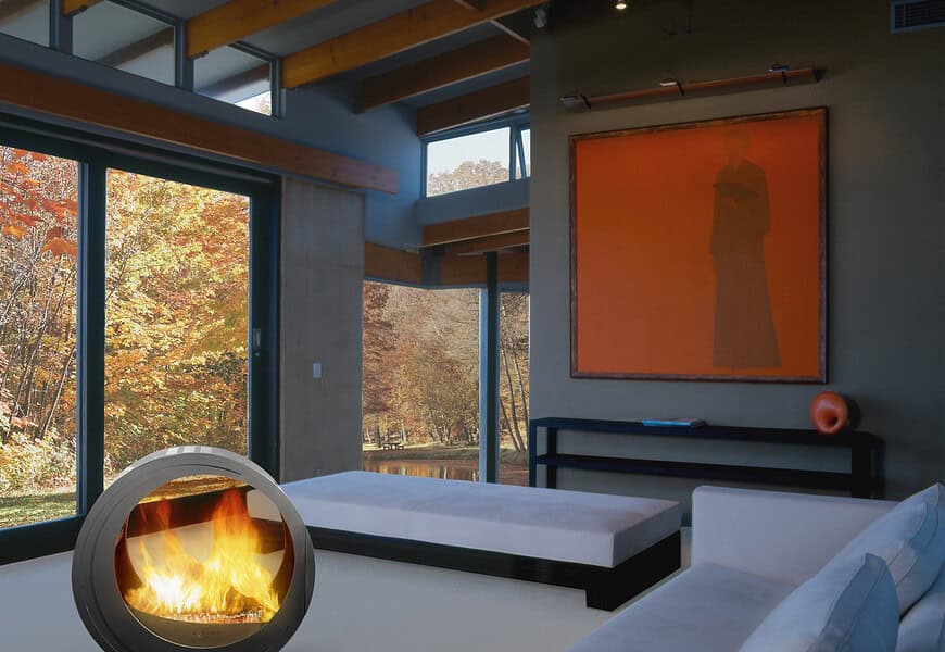 (chimenea Eclypsya en salón) Chimenea de leña nómada Arkiane modelo Eclypsya de diseño circular en salón contemporáneo con vistas al jardín otoñal