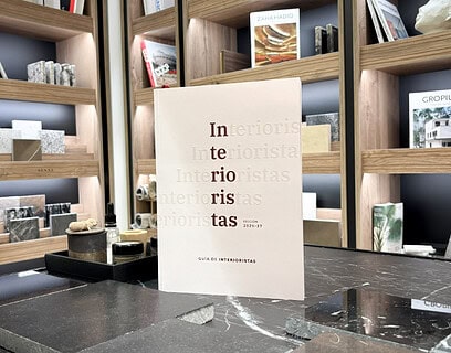 Ejemplar de la Guía de Interioristas 2026-2027 de Editorial Protiendas sobre encimera de mármol en el showroom de Cosentino