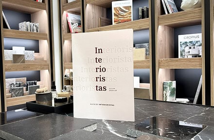 Ejemplar de la Guía de Interioristas 2026-2027 de Editorial Protiendas sobre encimera de mármol en el showroom de Cosentino