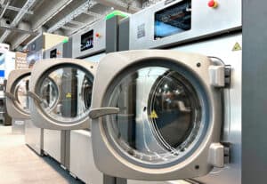 Lavadoras industriales Girbau de alta eficiencia con pantallas digitales expuestas en feria del sector
