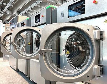 Lavadoras industriales Girbau de alta eficiencia con pantallas digitales expuestas en feria del sector