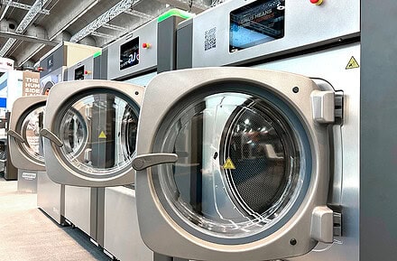Lavadoras industriales Girbau de alta eficiencia con pantallas digitales expuestas en feria del sector