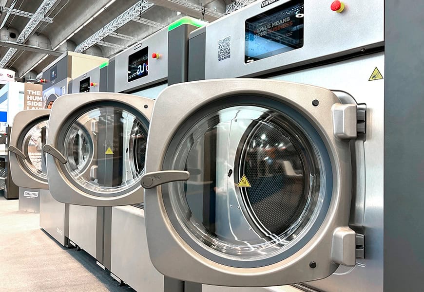 Lavadoras industriales Girbau de alta eficiencia con pantallas digitales expuestas en feria del sector