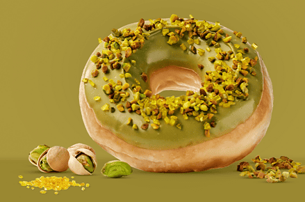 Donut Master Pistacho de Krispy Kreme con glaseado verde de pistacho y granillo de pistacho tostado Borges sobre fondo verde